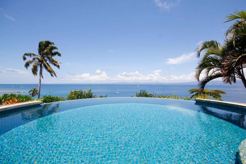 a swimming pool with a view of the ocean at Beachfront Villa - House of Bamboo, Infinity Pool in Savusavu