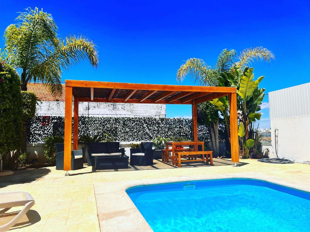 une terrasse avec une piscine et une pergola en bois dans l'établissement Villa Sol, à Ferragudo