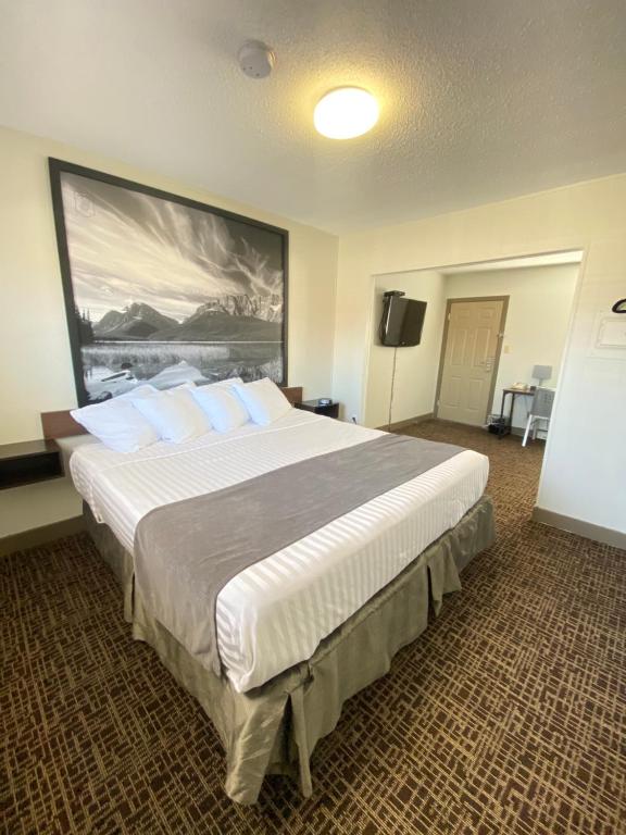 sypialnia z dużym łóżkiem i dużym obrazem na ścianie w obiekcie Super 8 by Wyndham Penticton w mieście Pentiction