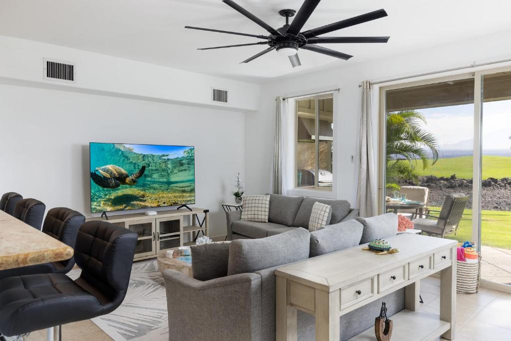 een woonkamer met een bank en een plafondventilator bij Hilton Pool Pass Included - Luxury Living on the Green w Pool Hot Tub & Views in Waikoloa