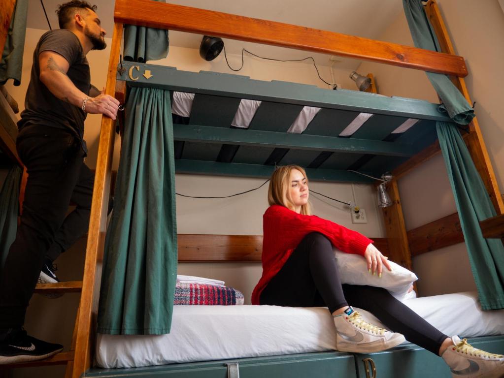 une femme assise au-dessus d'un lit superposé dans l'établissement Green Tortoise Hostel Seattle, à Seattle