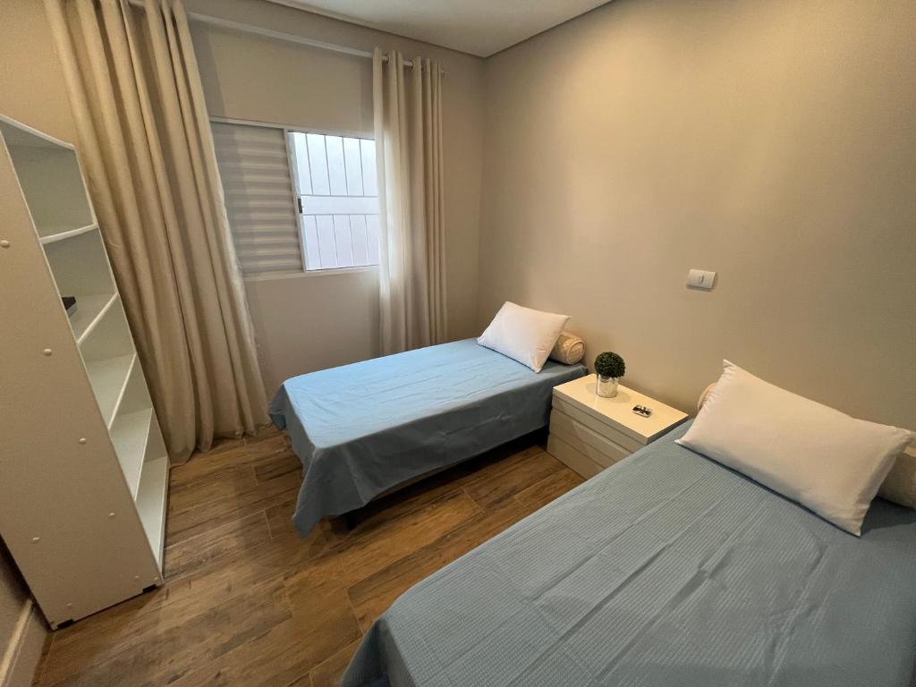 um pequeno quarto com 2 camas e uma janela em Casa Nova - Excelente Localização em Piracicaba