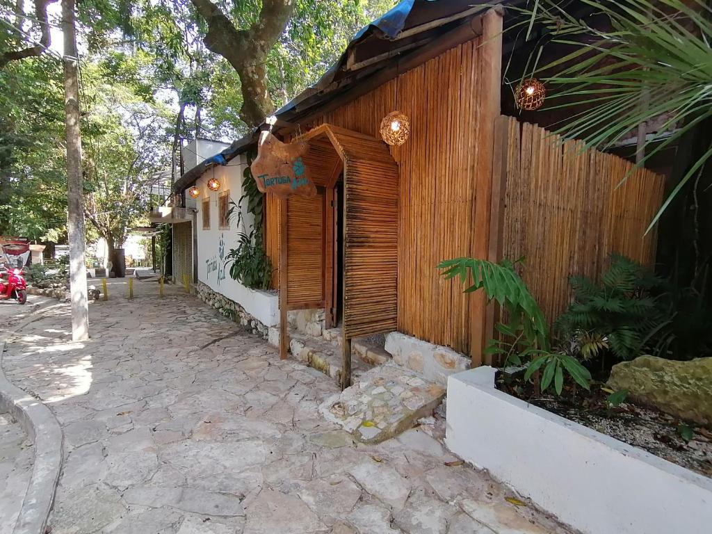 a wooden building with a stone walkway in front of it at Casa Tortuga Azul in Palenque