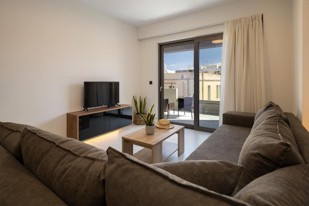 uma sala de estar com um sofá e uma televisão em Ruby Luxury Suites em Chania