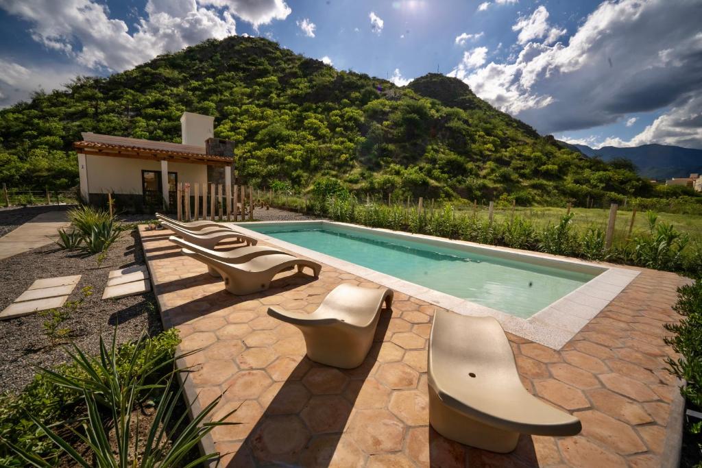 a swimming pool with two chairs and a house at Complejo Los Olivos - casa 3 y 4 in Cafayate