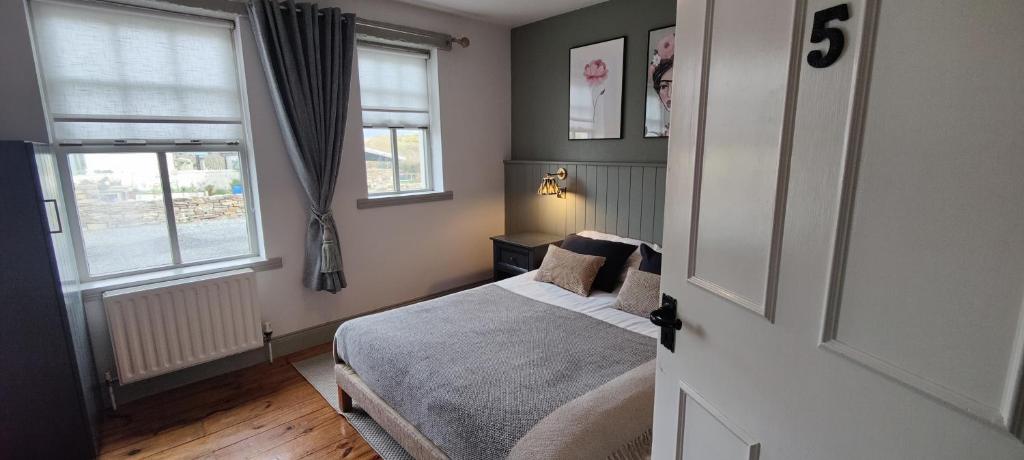 a small bedroom with a bed and two windows at Corcreggan Mill Lodge in Dunfanaghy