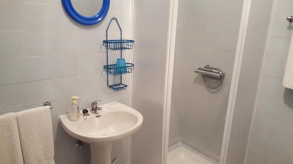 uma casa de banho branca com um lavatório e um chuveiro em Alojamento Dona Inês de Castro em Atouguia da Baleia