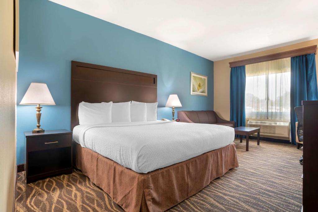 a hotel room with a large bed and a chair at Best Western Ville Platte in Ville Platte