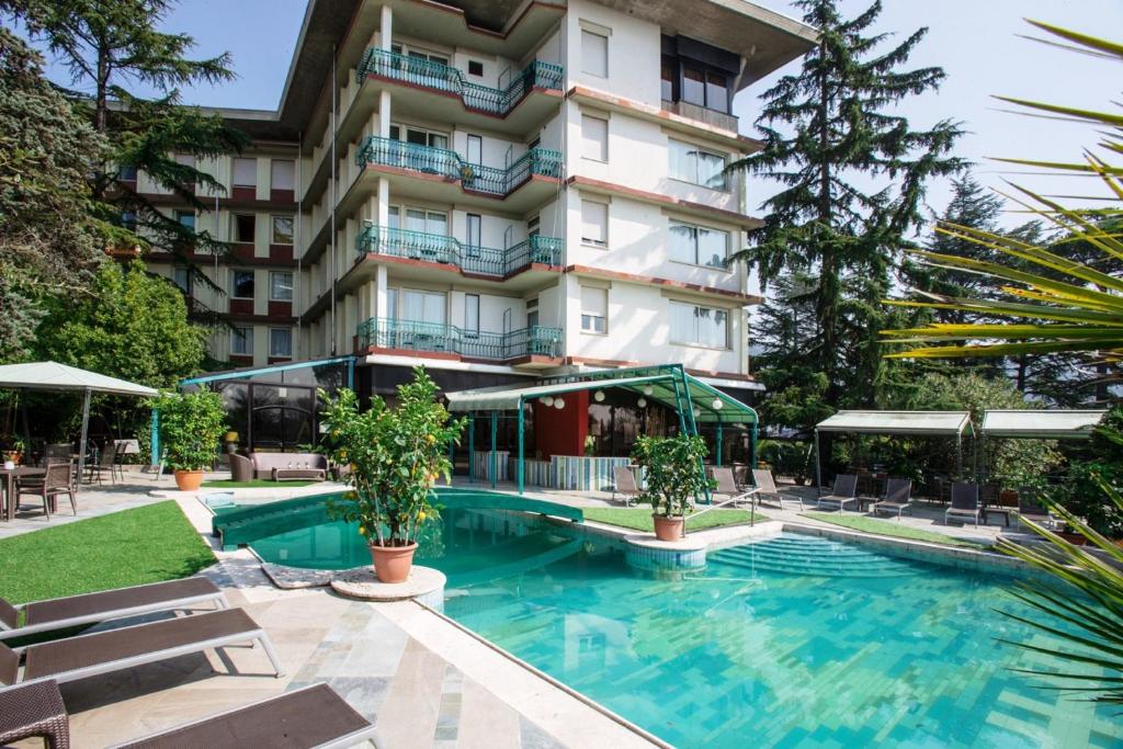 un hôtel avec une piscine en face d'un bâtiment dans l'établissement Grand Hotel Panoramic, à Montecatini Terme