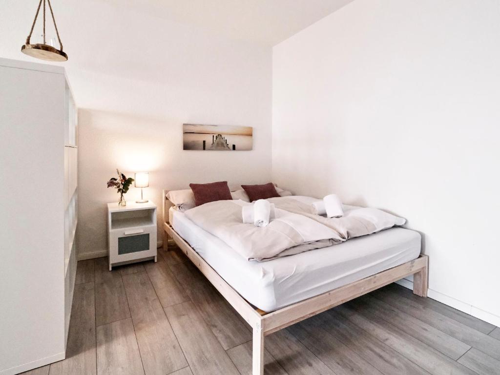 Habitación blanca con cama y mesita de noche en Küstenliebe en Flensburg