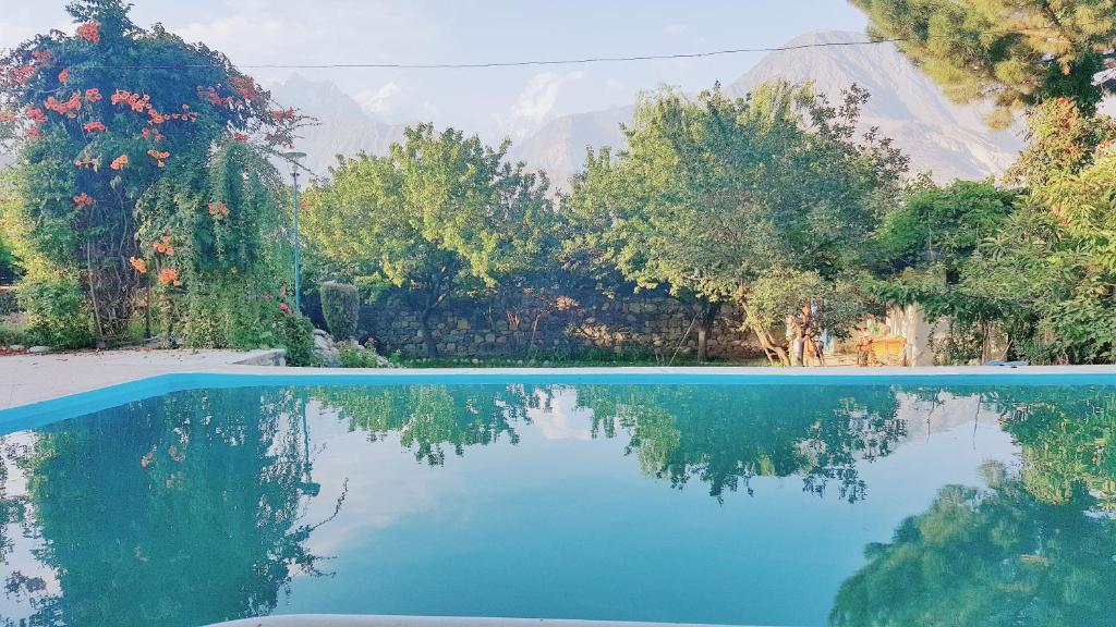 una piscina de agua con árboles y montañas al fondo en Serene Guest House en Gilgit