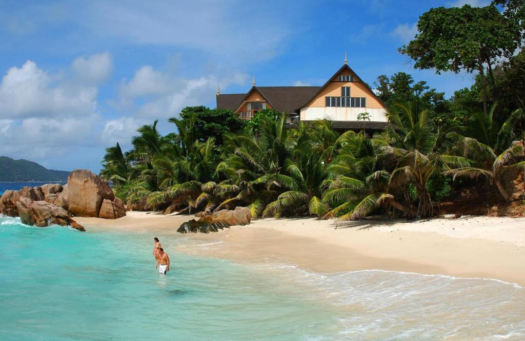 a person on a surfboard in front of a beach at Patatran Village Hotel in La Digue