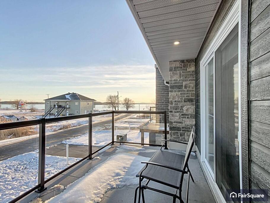 a balcony with a chair and a table and snow at Luxurious River-view Townhouse in Cornwall