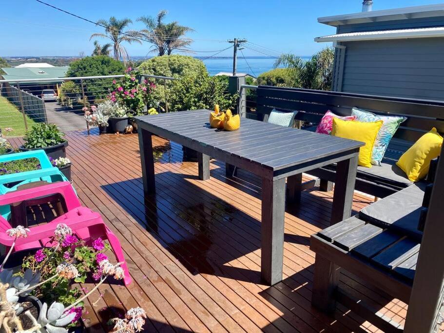 una terrazza in legno con tavolo e sedie. di Salty Paws Dog Friendly Luxe Cottage a San Remo