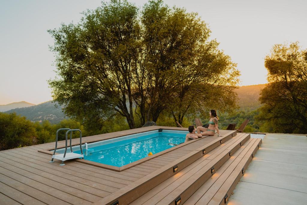 a woman and a child sitting next to a swimming pool at Boho chic oasis by Casa Oso with pool, spa and views in Ahwahnee