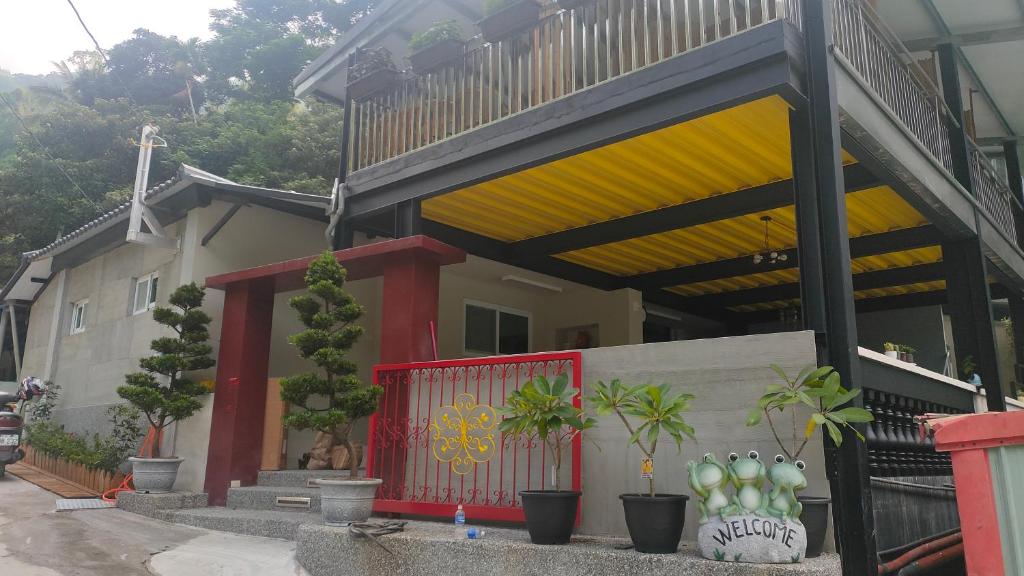 una casa con una puerta roja y plantas delante de ella en 白玉湯屋, en Wenquan