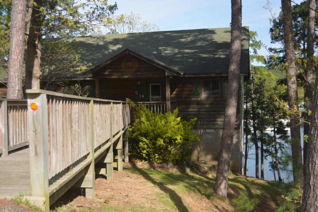 une maison en bois avec une clôture en bois et une terrasse couverte dans l'établissement C14, Two bedroom, two bath, log-sided, luxury Harbor North cottage overlooking the lake, cottage, à Mount Ida