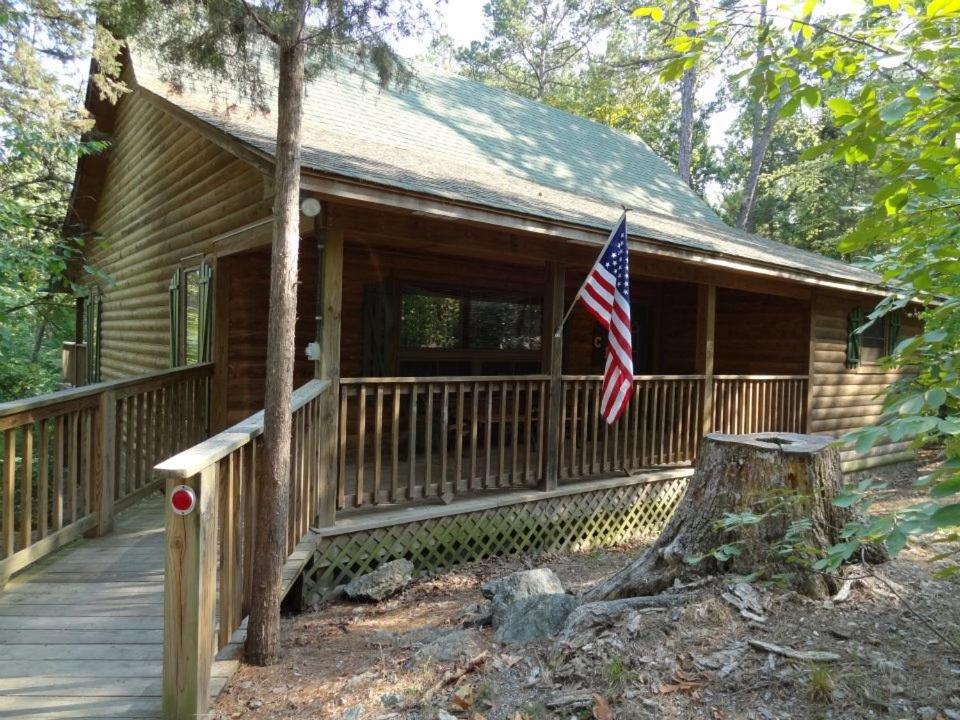 a house with an american flag on a porch at C19, One bedroom luxury, log-sided Couple's Cottage with private hot tub and unique extras cottage in Mount Ida