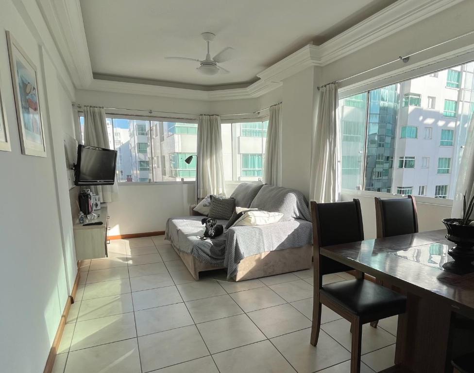 uma sala de estar com uma cama, uma mesa e janelas em Apartamento 2 quartos completo 200 m da praia em Capão da Canoa