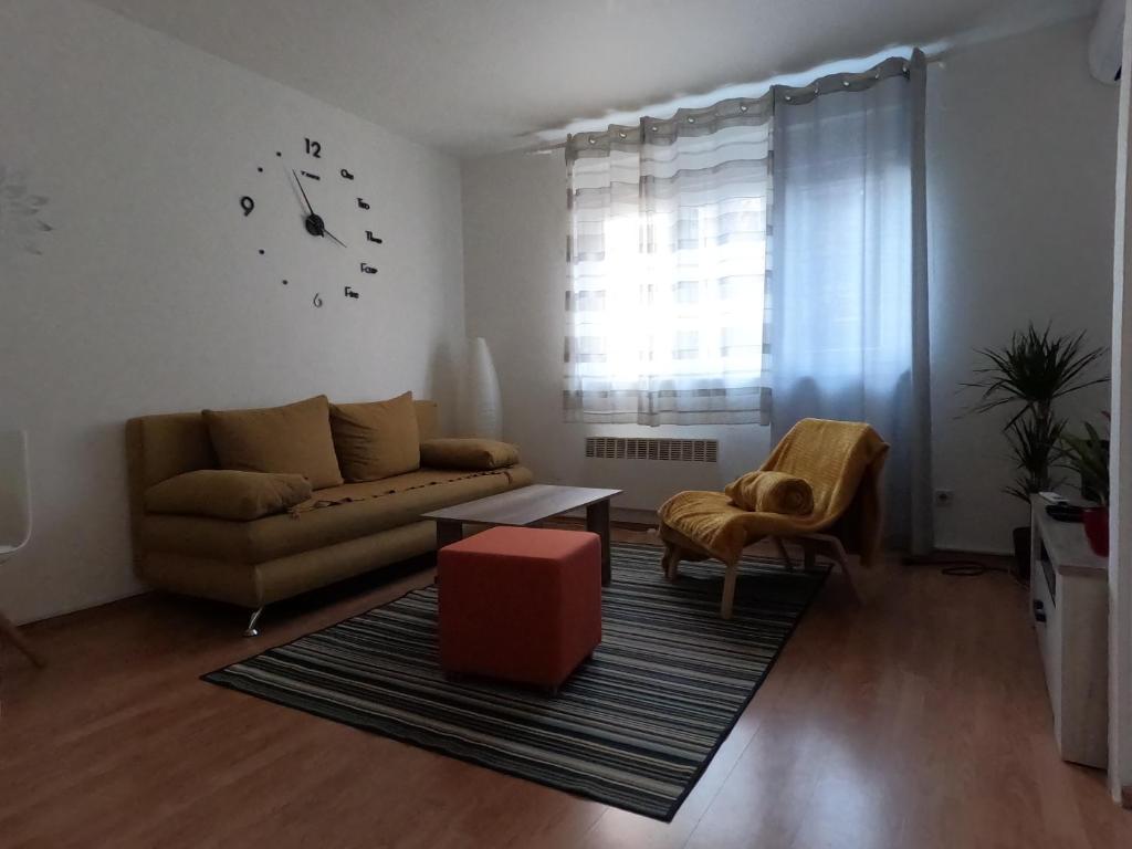 uma sala de estar com um sofá e um relógio na parede em Folka cozy apartment em Zagreb