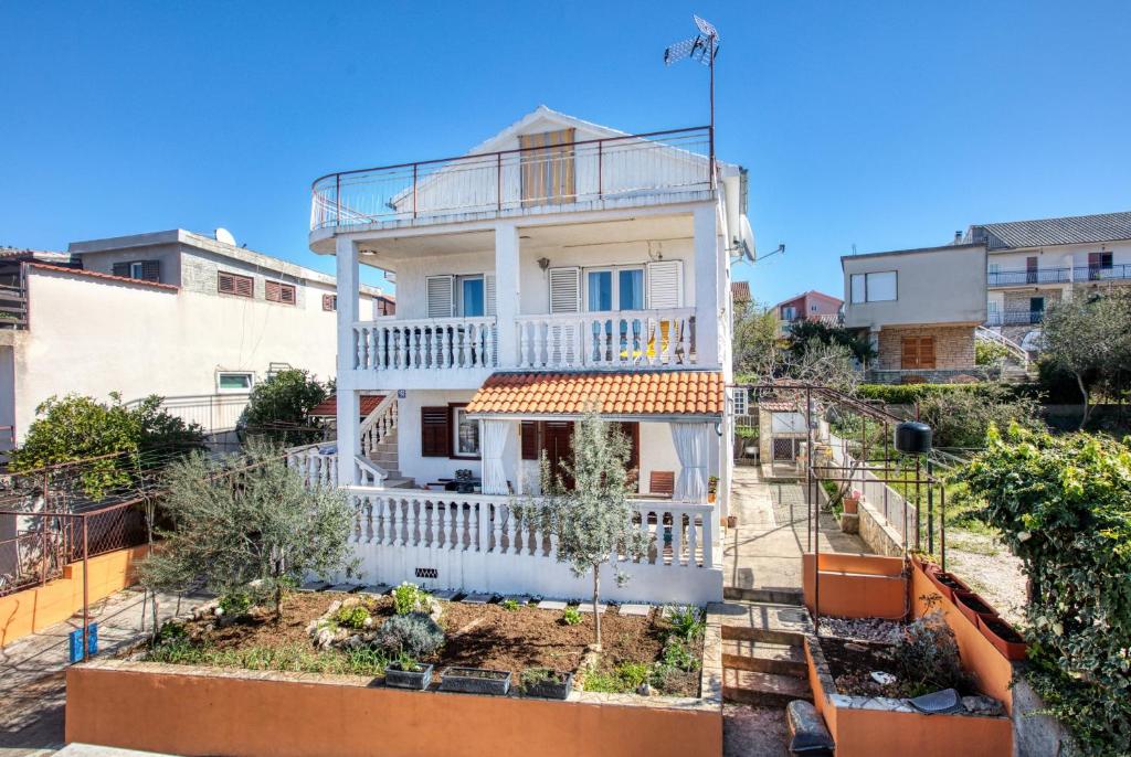 a white house with a balcony on a city street at Apartments by the sea Grebastica, Sibenik - 11463 in Grebaštica