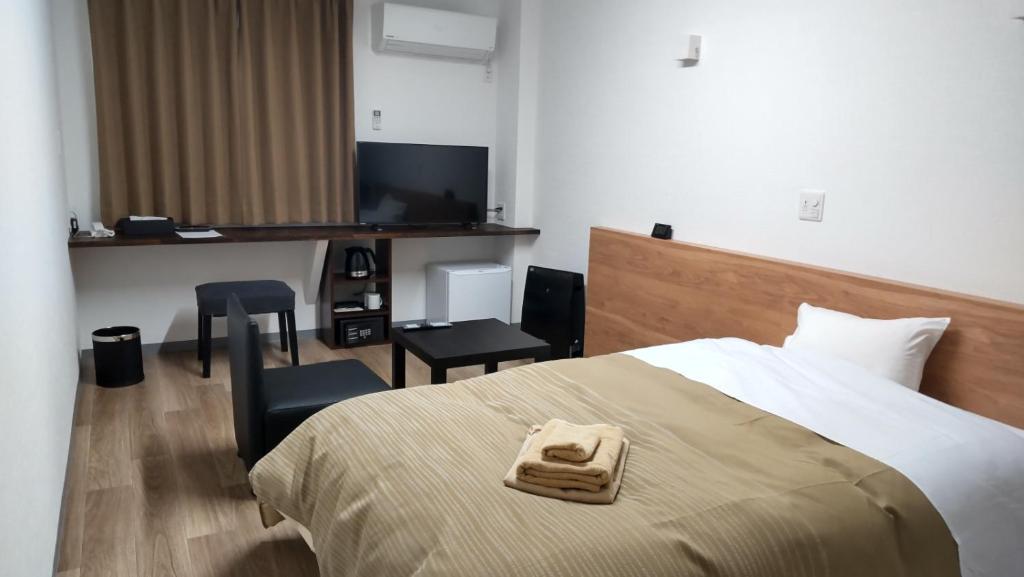 een hotelkamer met een bed en een bureau bij Basic Hotel Chichibu in Chichibu