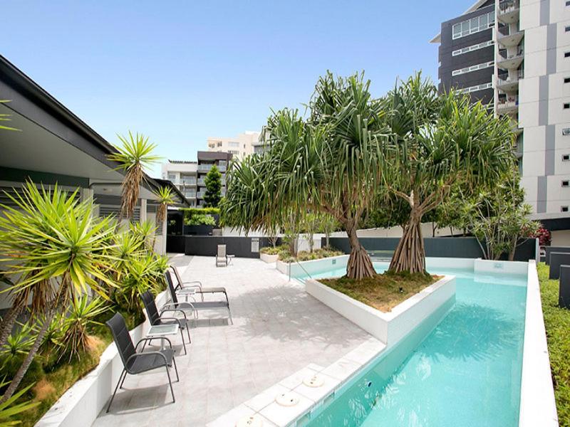 un patio con sillas y árboles y una piscina en Story Apartments, en Brisbane