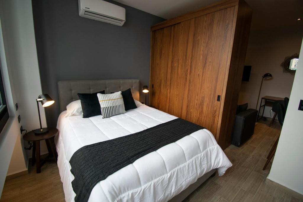 a bedroom with a large bed with black and white pillows at Punto Lofts Periférico Sur in Mexico City