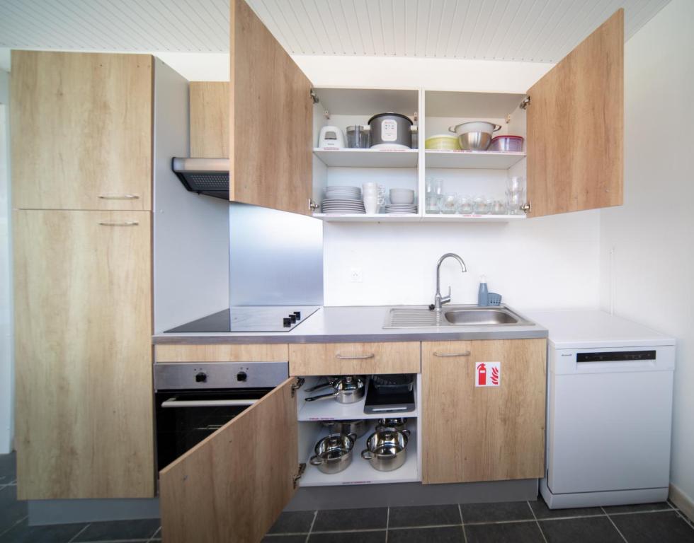 a kitchen with wooden cabinets and a sink and a dishwasher at La Perle du Cap in Case-Pilote
