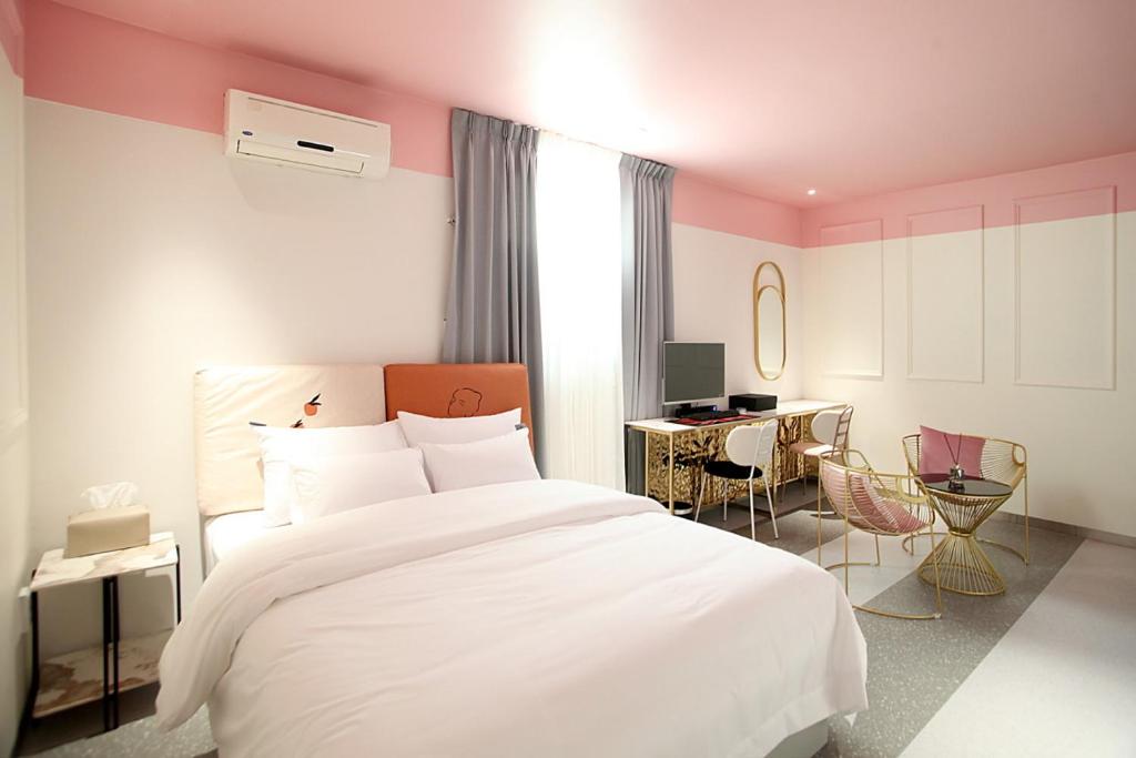 a bedroom with a white bed and a desk at Baba Hotel Gimcheon in Gimcheon
