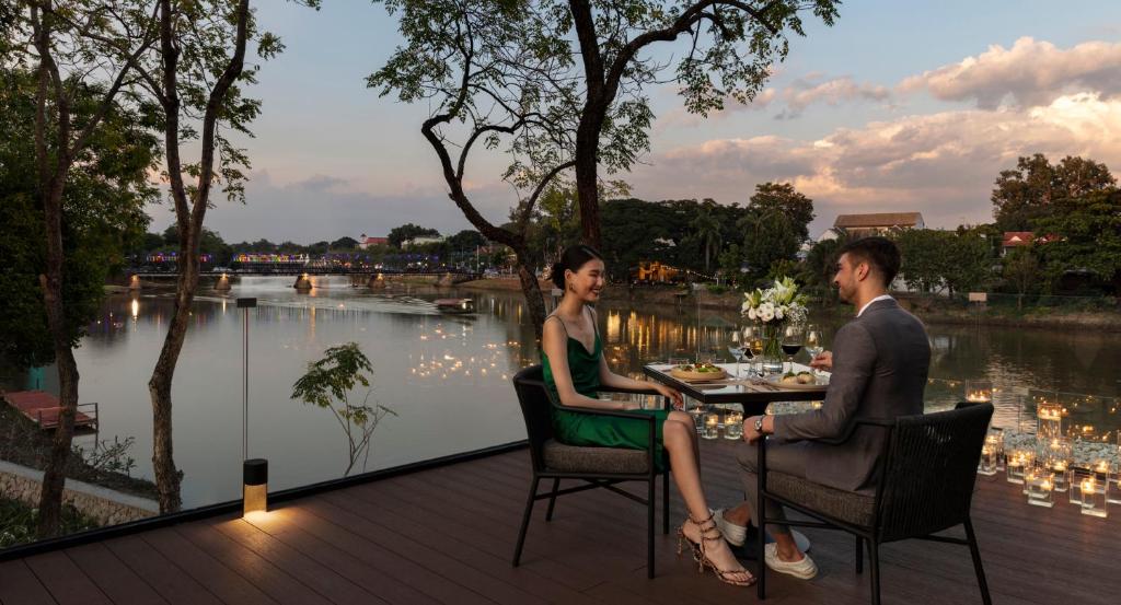 a man and woman sitting at a table in front of a lake at Anantara Chiang Mai Resort in Chiang Mai