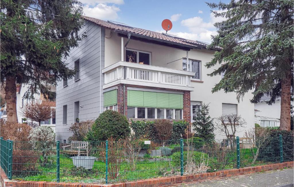 ein weißes Haus mit einem grünen Zaun davor in der Unterkunft Pet Friendly Apartment In Ober Ramstadt With Kitchen in Ober-Ramstadt