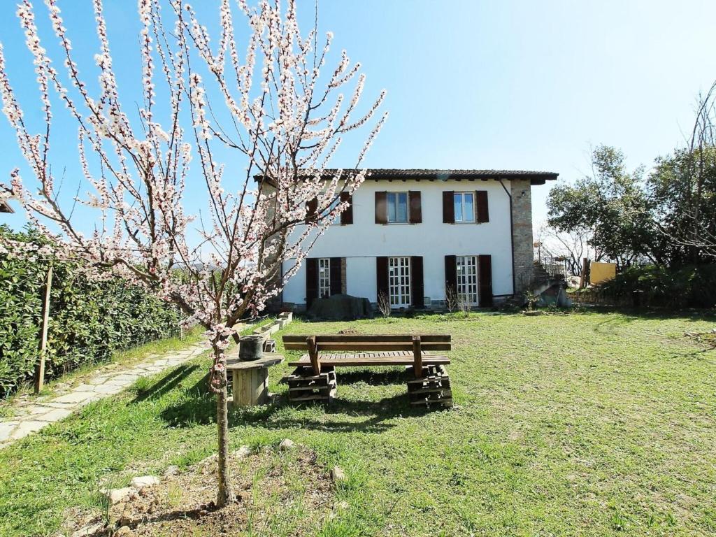 a house with a bench and a tree in front of it at Rustic Holiday Home in Montemarzino with Garden in Casasco