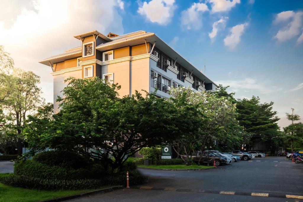 un bâtiment jaune avec des voitures garées dans un parking dans l'établissement โรงแรมสินสิริ ปัญญา-รามอินทรา, à Ban Bang Chan