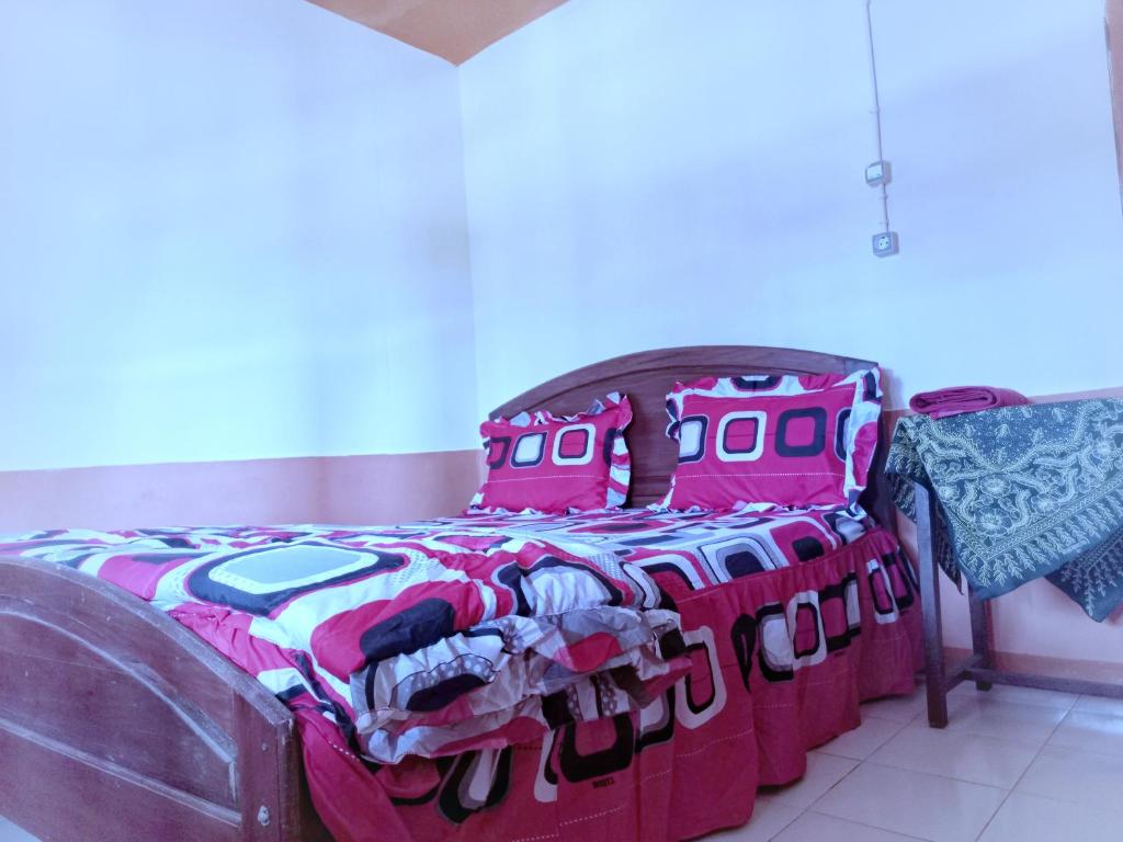 a bed with a colorful comforter and pillows on it at Sun Rice Homestay in Ruteng