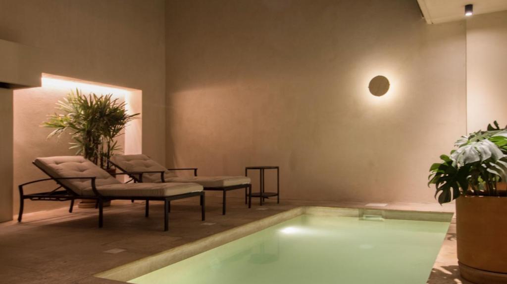a room with a swimming pool with chairs and plants at Casa Nova Centro Oaxaca - Adults Only in Oaxaca City