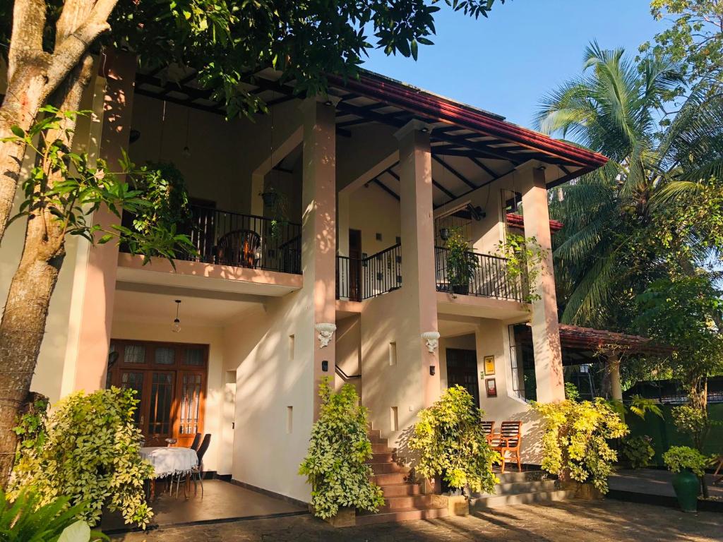 uma grande casa branca com um alpendre e árvores em West Dene em Negombo