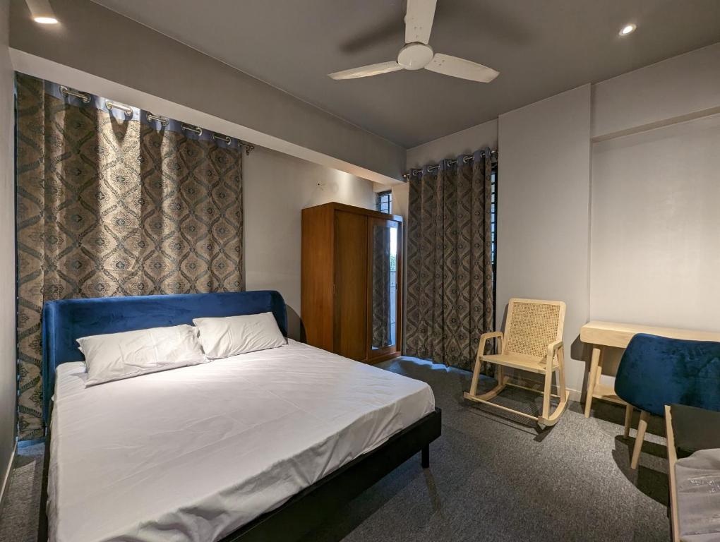 una camera con letto, sedia e ventilatore a soffitto di GreyRooms a Dhaka