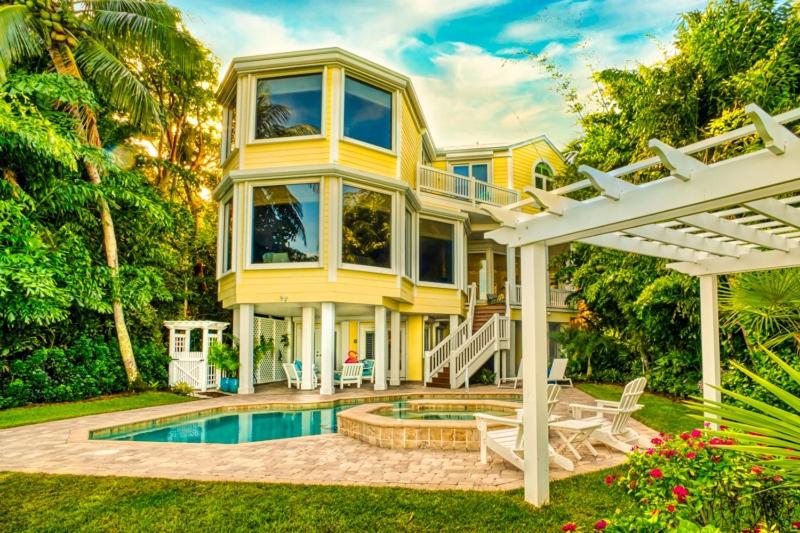 une grande maison jaune avec une piscine dans la cour dans l'établissement Captiva Grace home, à Captiva