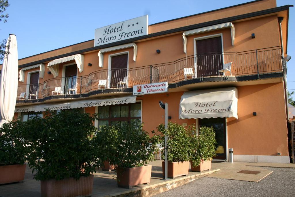 a building with potted trees in front of it at Hotel Moro Freoni in San Pietro in Cariano