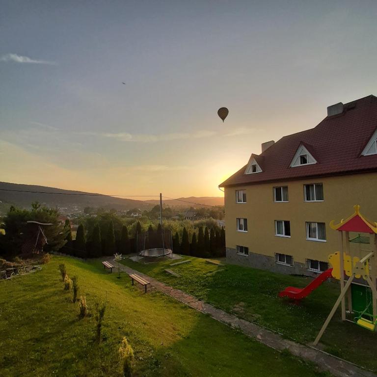 a hot air balloon flying over a house with a playground at Вілла Мозола in Skhidnitsa