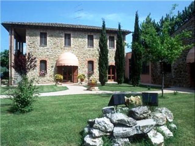 una gran casa de piedra con una pared de piedra en el patio en Hotel Villalago trasimeno en Magione
