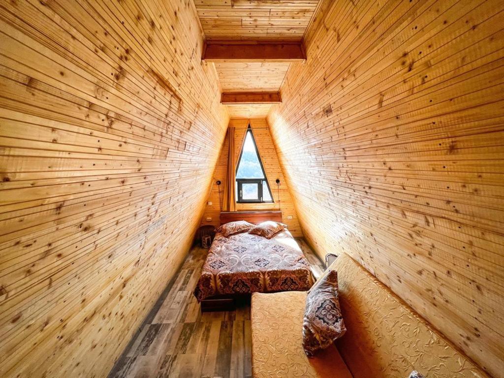 a small room with a bed in a wooden wall at Cabana A-Frame Refugiu Montan in Băişoara