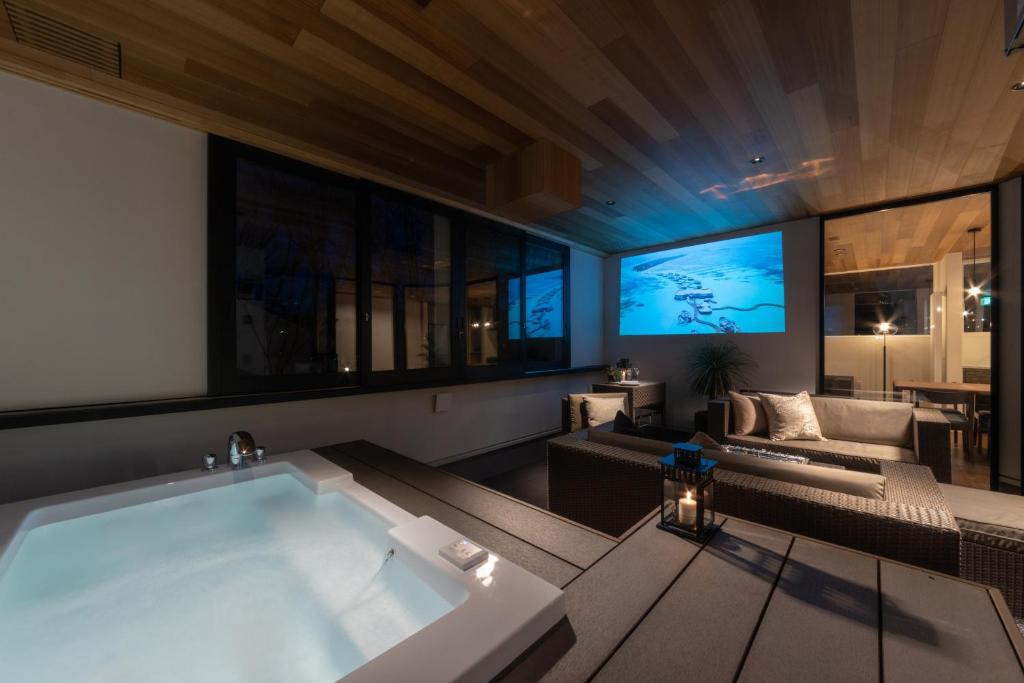 uma grande banheira numa sala de estar com televisão em Le Sauna Villa Hakuba em Hakuba