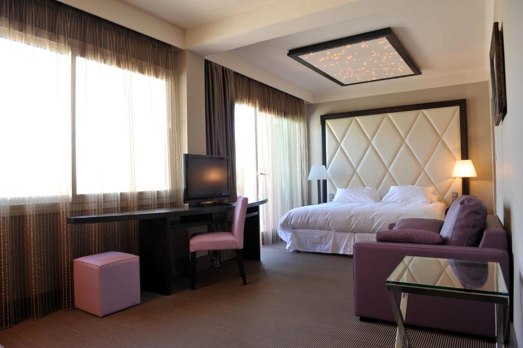 Cette chambre comprend un lit, un bureau et un canapé. dans l'établissement Le Safari Hotel Restaurant, à Carpentras