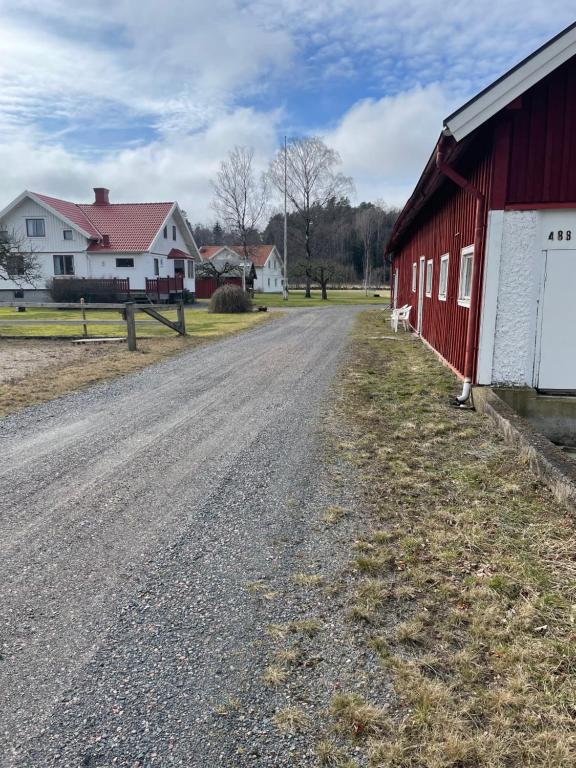 un camino de tierra junto a un granero rojo en Persgård lägenhet övervåning en Kungsbacka