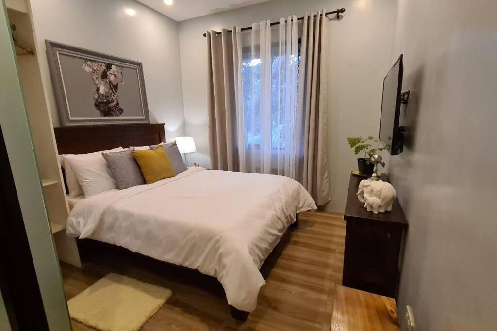 - une chambre avec un grand lit et une fenêtre dans l'établissement The Great Molave DELUXE ROOM, à Cavite