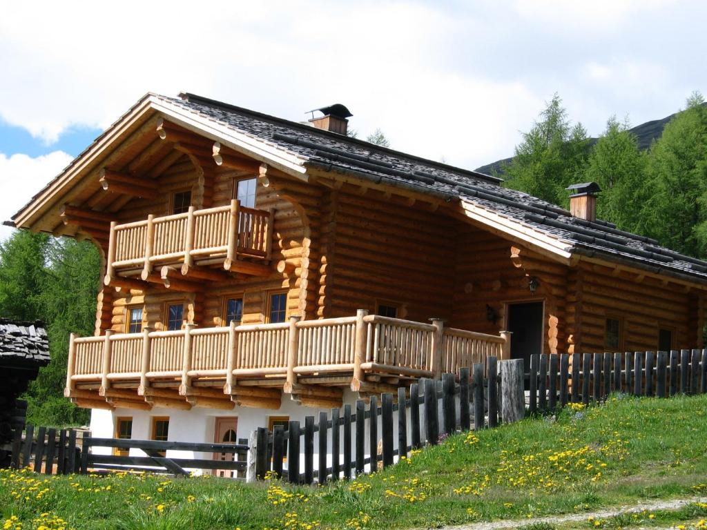 a log cabin with a balcony and a fence at Tomperkasa in Apriach