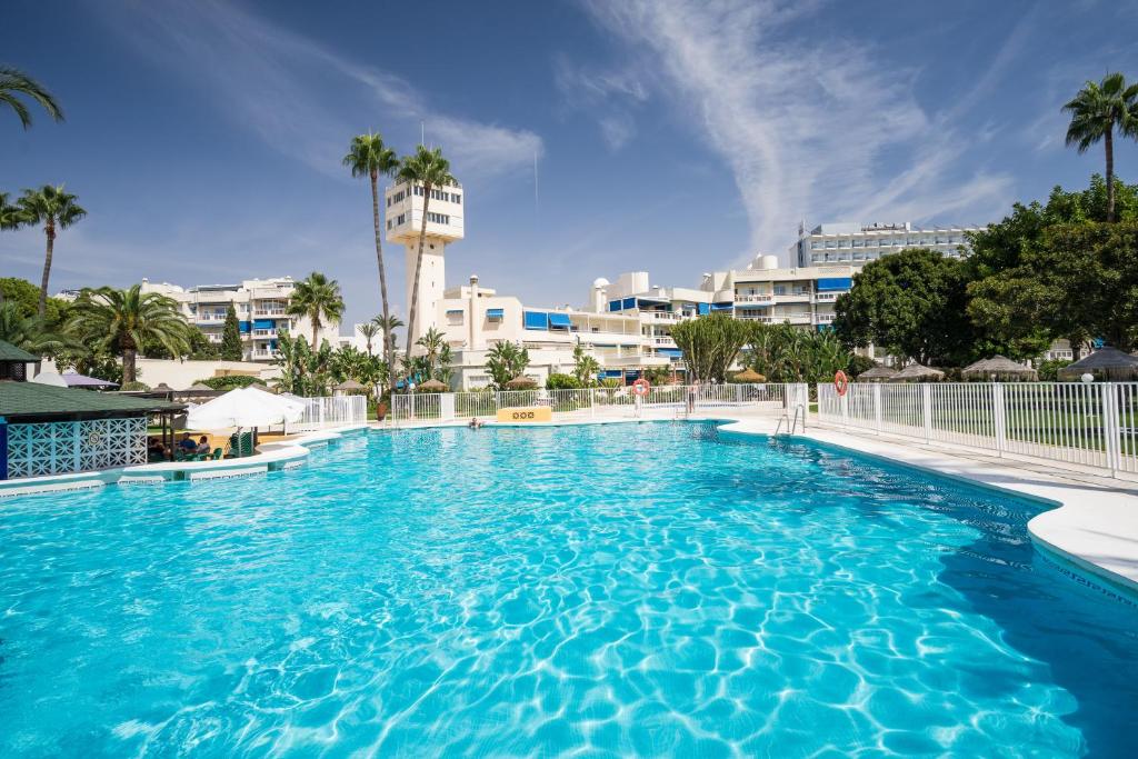 una grande piscina blu con edifici sullo sfondo di Espectacular primera linea de playa a Torremolinos