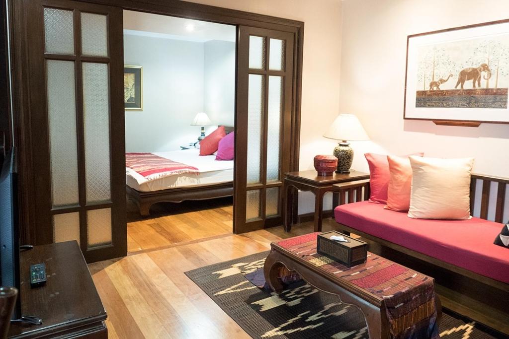 sala de estar con sofá, cama y espejo en The Siam Heritage Hotel, en Bangkok